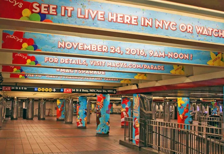 Subway concourse hung with Thanksgiving Day Parade banners reading “See it live here in NYC”